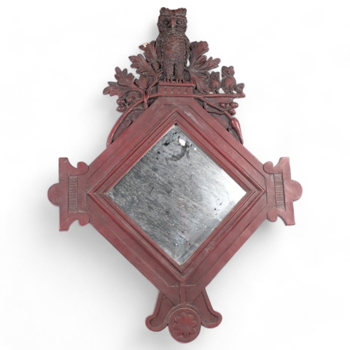 114 - A stained resin-framed lozenge wall mirror, surmounted by a family of owls, H96cm