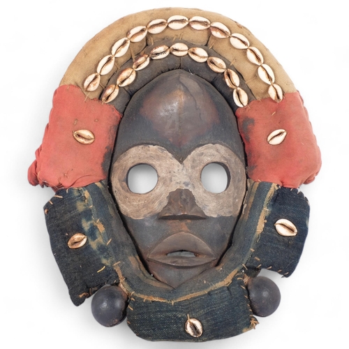 44 - A Dan hardwood Tribal mask in cowrie shell and textile surround, height 31cm