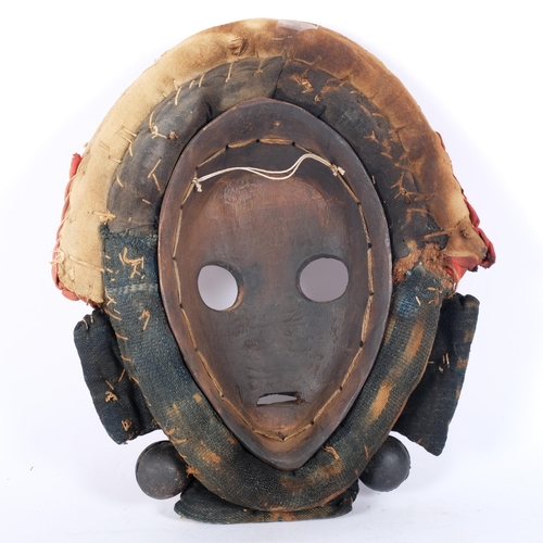 44 - A Dan hardwood Tribal mask in cowrie shell and textile surround, height 31cm