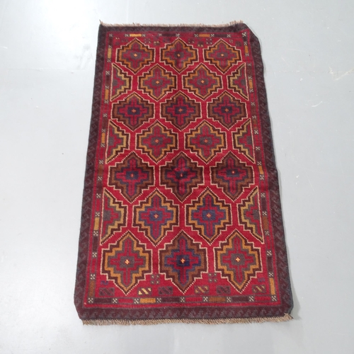 2309 - A red ground Baluchi rug, 128x74cm.