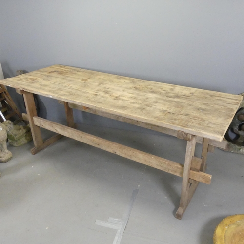 3430 - A large pine plank-top trestle table, of pegged construction. 228x85x83cm.