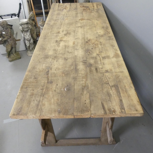 3430 - A large pine plank-top trestle table, of pegged construction. 228x85x83cm.