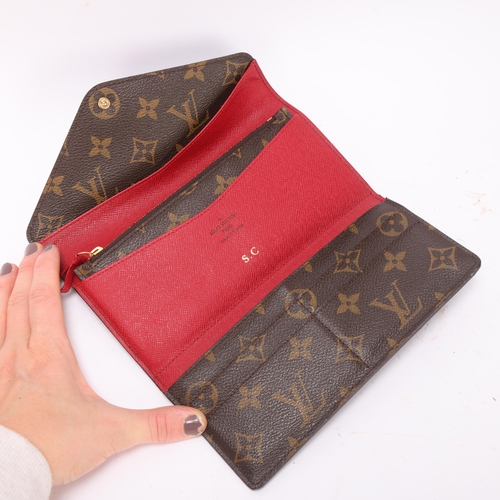 419 - A Louis Vuitton Sarah wallet, in brown monogram leather, with red leather covered leather and interi... 