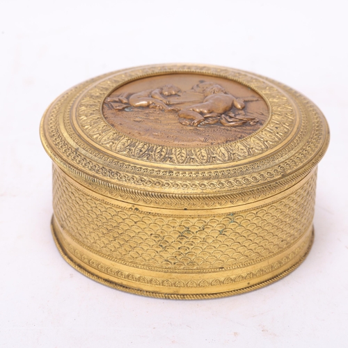 523 - A French 19th century circular gilt-bronze box, with relief decorated lid and mirror inside, diamete... 