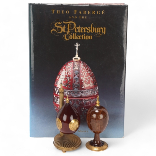 540 - Theo Faberge, 2 ornamental eggs, specimen wood and brass, largest height 14cm, together with a book