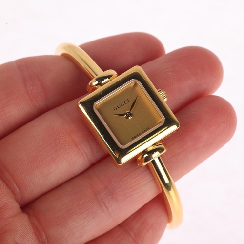 1027 - GUCCI - a lady's gold plated stainless steel 1900L quartz bangle watch, champagne dial with leaf han... 