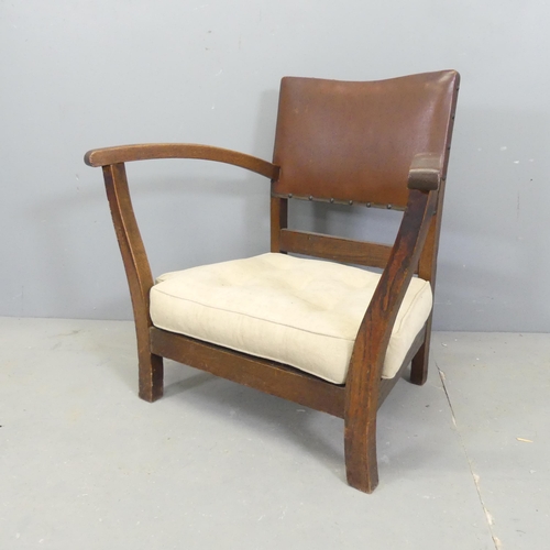 2501 - An Art Deco oak low armchair, with studded brown leather upholstered back and drop-in cushion.