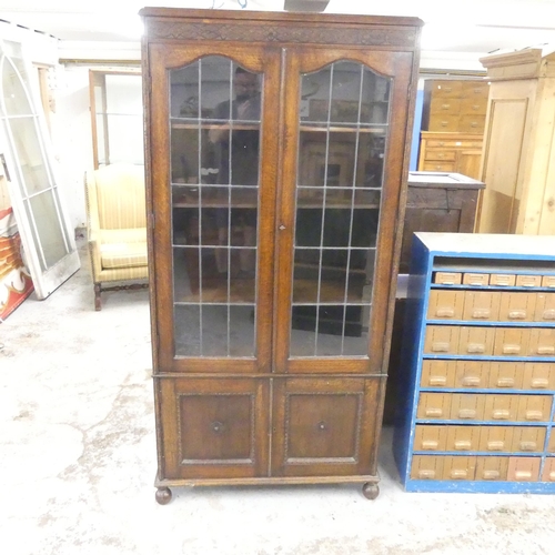 2545 - An early 20th century oak bookcase, with two lattice glazed doors and cupboards under. 94x189x32cm.