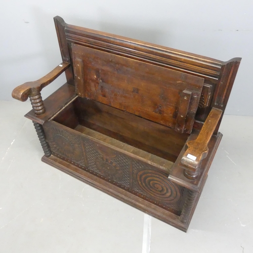 2519 - An early 20th century Breton French panelled oak hall bench, with lifting seat and carved decoration... 