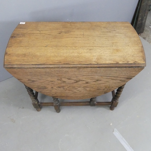 2559 - An early 20th century oak oval gate-leg table with barley twist legs. 92x74x48cm.