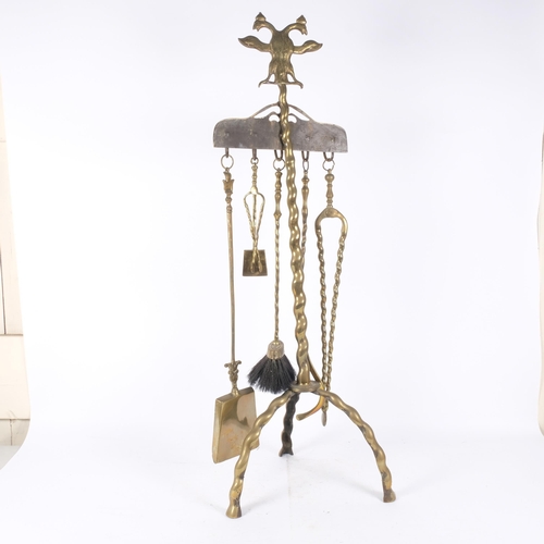 124 - A polished brass floor-standing companion set, with 6 various tools, stand surmounted by double-head... 