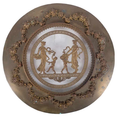 247 - An Antique circular brass and glass plaque, with applied swag and rose decoration and Grecian figure... 