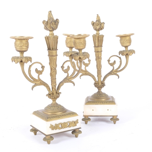 70 - A pair of Empire style gilt-brass 2-branch table candelabras, on white marble bases and gilt feet, H... 