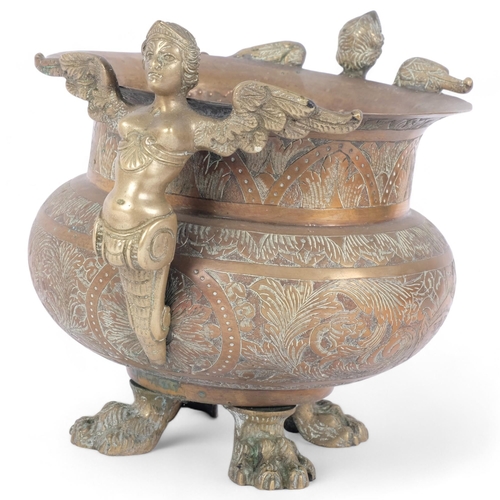 78 - A 19th century heavy engraved brass cauldron, with winged figure handles, raised on cast paw feet, H... 