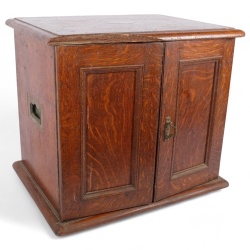 97 - An early 20th century panelled oak 2-door table-top cabinet, with a partially fitted interior, 56cm