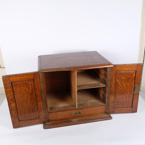 97 - An early 20th century panelled oak 2-door table-top cabinet, with a partially fitted interior, 56cm