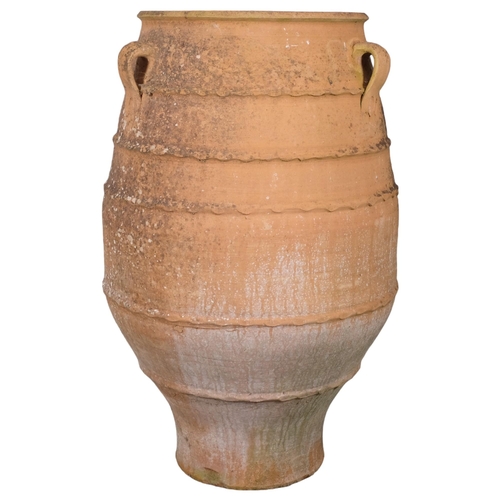 2804 - A large weathered terracotta olive oil jar, with three handles and ribbed decoration. 60x92cm.