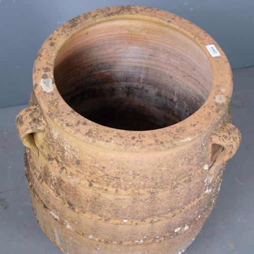 2804 - A large weathered terracotta olive oil jar, with three handles and ribbed decoration. 60x92cm.