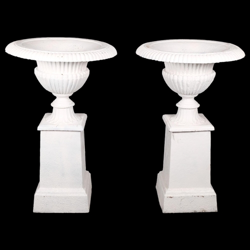 A pair of antique two section painted cast iron Campana style urns on stands, with reeded decoration and raised on tapered pedestal bases. Overall 60x93cm.