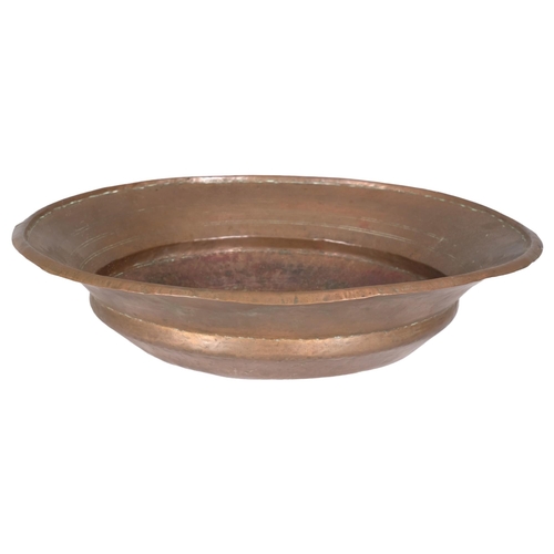 2830 - An Arts & Crafts style spun and beaten copper bowl. 52x13cm.