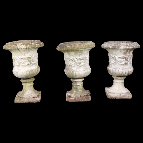 2904 - A set of three painted and weathered concrete garden urns on stands, with egg and tongue decoration.... 