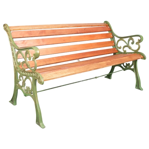 2985 - A mahogany-slatted garden bench with painted cast-iron ends. 145x77x70cm.