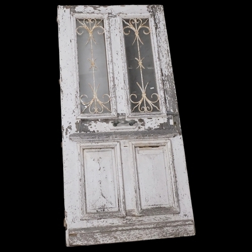 2976 - A painted pine door, with glazed and wrought iron panels. 101x210cm.