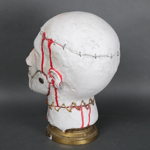 3041 - Curiosity/Macabre : A sculptured severed Horror head mounted on brass base, height 32cm.