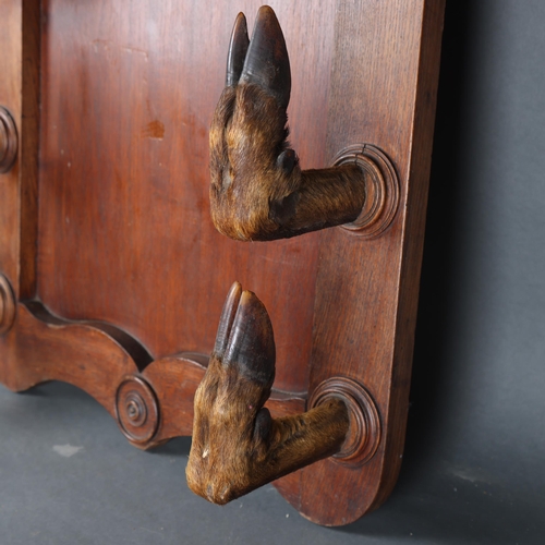 3175 - Taxidermy: Deer Hoof Coat / Gun Rack. 
A large oak panel with eight large red deer hoof slots, each ... 