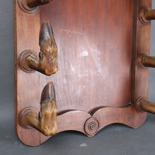 3175 - Taxidermy: Deer Hoof Coat / Gun Rack. 
A large oak panel with eight large red deer hoof slots, each ... 