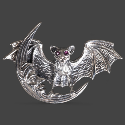 3240 - Curiosity/Macabre: Silver Pendant / Brooch in the form of a bat with facet cut pink sapphire or ruby... 