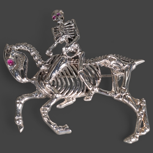 3242 - Curiosity/Macabre: Silver Brooch in the form of a skeleton rider with pink ruby chip eyes, riding ho... 