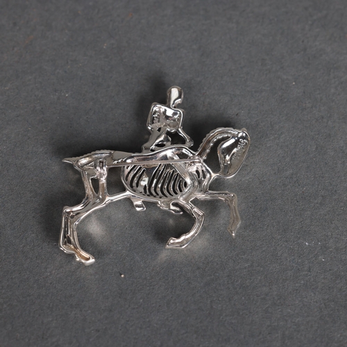 3242 - Curiosity/Macabre: Silver Brooch in the form of a skeleton rider with pink ruby chip eyes, riding ho... 