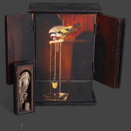 3568 - Jackie Attwood - a small painted wooden display housing a mummified Goldfinch skeleton, metallic cha... 