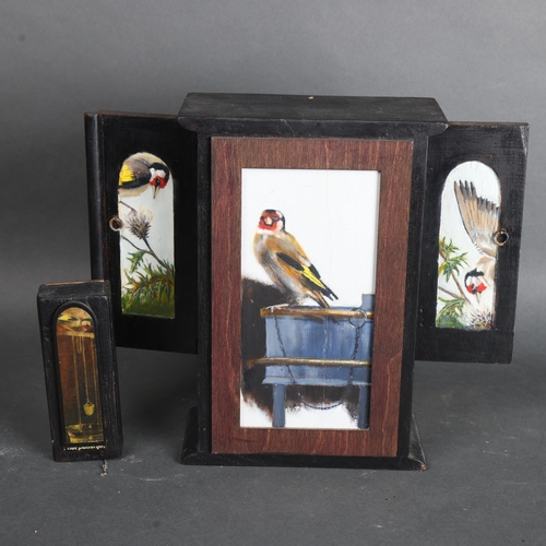 3568 - Jackie Attwood - a small painted wooden display housing a mummified Goldfinch skeleton, metallic cha... 