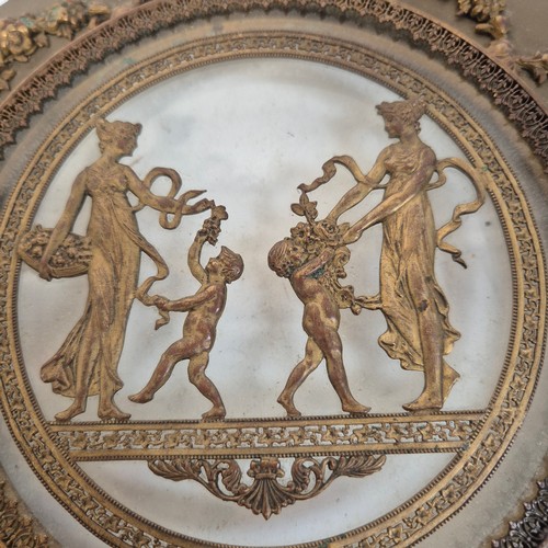 247 - An Antique circular brass and glass plaque, with applied swag and rose decoration and Grecian figure... 