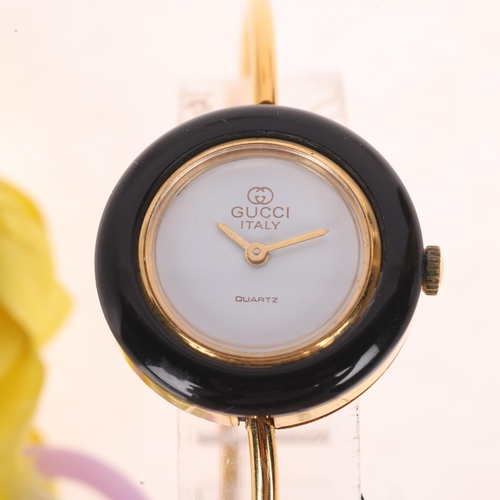 1034 - GUCCI - a lady's Vintage gold plated quartz bangle wristwatch, white dial with pencil hands and inte... 