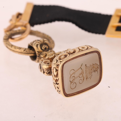 1121 - An Antique 15ct gold black silk watch fob chain, with hardstone intaglio seal fob and foliate split ... 