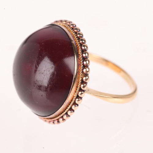 1142 - An Antique 9ct gold garnet dress ring, set with foil-back round cabochon garnet within beaded edge c... 