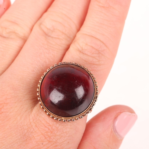 1142 - An Antique 9ct gold garnet dress ring, set with foil-back round cabochon garnet within beaded edge c... 