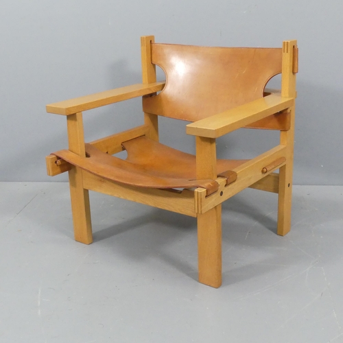 GUNNAR GUDMUNDSSON, a mid-century “Chief” safari style lounge chair in oak with saddle leather sling seat and back, made by Kristiani Siggierson of Reykjavik, Iceland, 1960, height 71cm , width 69cm, depth 69cm.