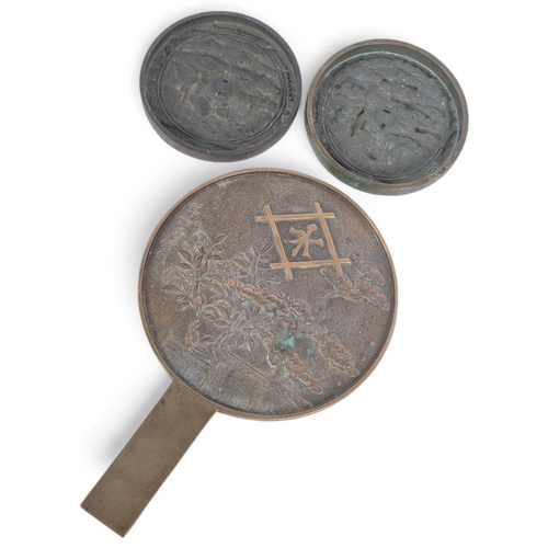 173 - 2 Chinese relief cast-bronze mirrors, and another similar hand mirror, 30cm (3)