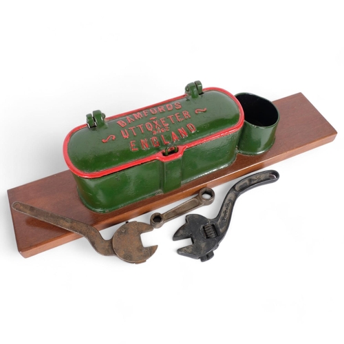 58 - A Bamfords stationary engine painted cast-iron toolbox, containing various spanners, mounted on wood... 