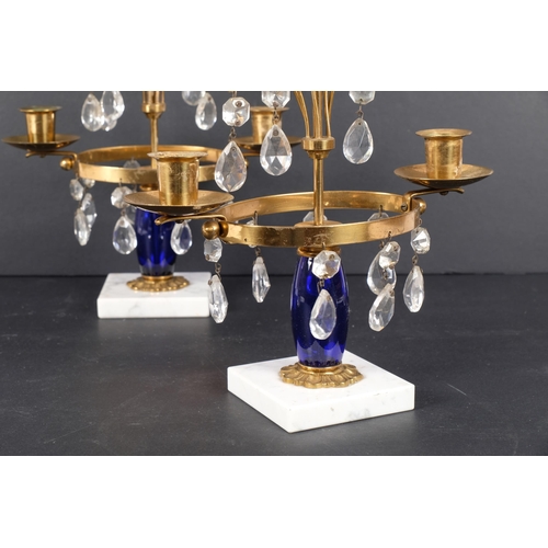 217 - A pair of blue glass and brass table candelabra, with white marble bases, H32cm