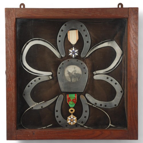 256 - A military cabinet display of horseshoes, medals and spurs, cabinet dimensions 46cm x 46cm