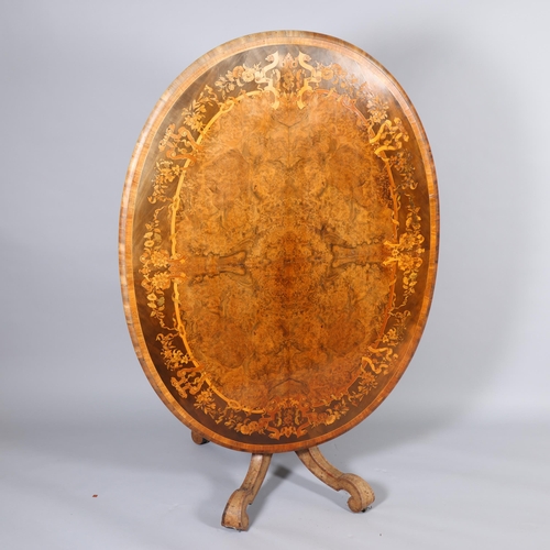 175 - A Victorian burr walnut oval tilt-top dining table, intricate marquetry inlaid top on carved quadrup... 