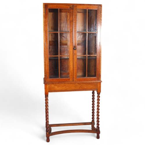 437 - A Cotswold School English walnut and glazed display cabinet on fine barley twist legs with a cast br... 