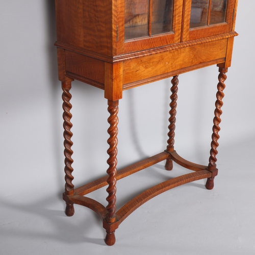 437 - A Cotswold School English walnut and glazed display cabinet on fine barley twist legs with a cast br... 