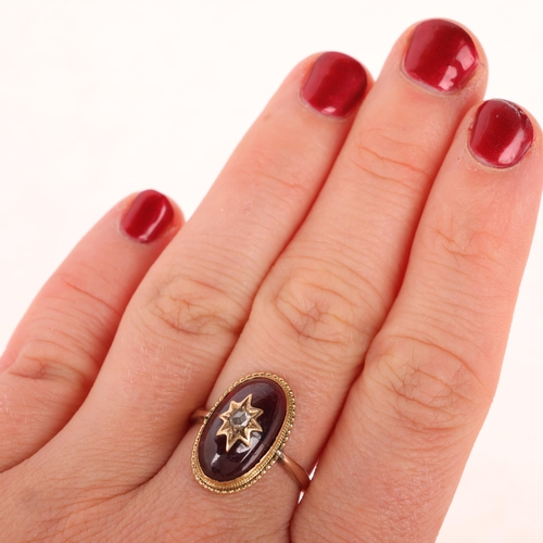 1106 - An Antique Victorian garnet and diamond mourning ring, circa 1880, set with foil-back oval cabochon ... 