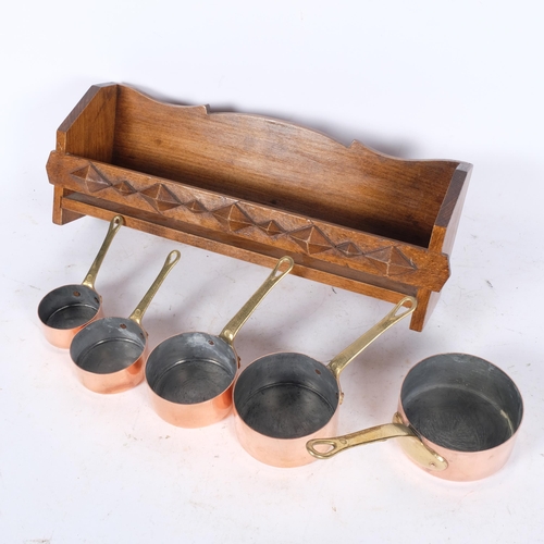 440 - A graduated set of 5 copper and brass saucepans, on wall-hanging rack, W41cm